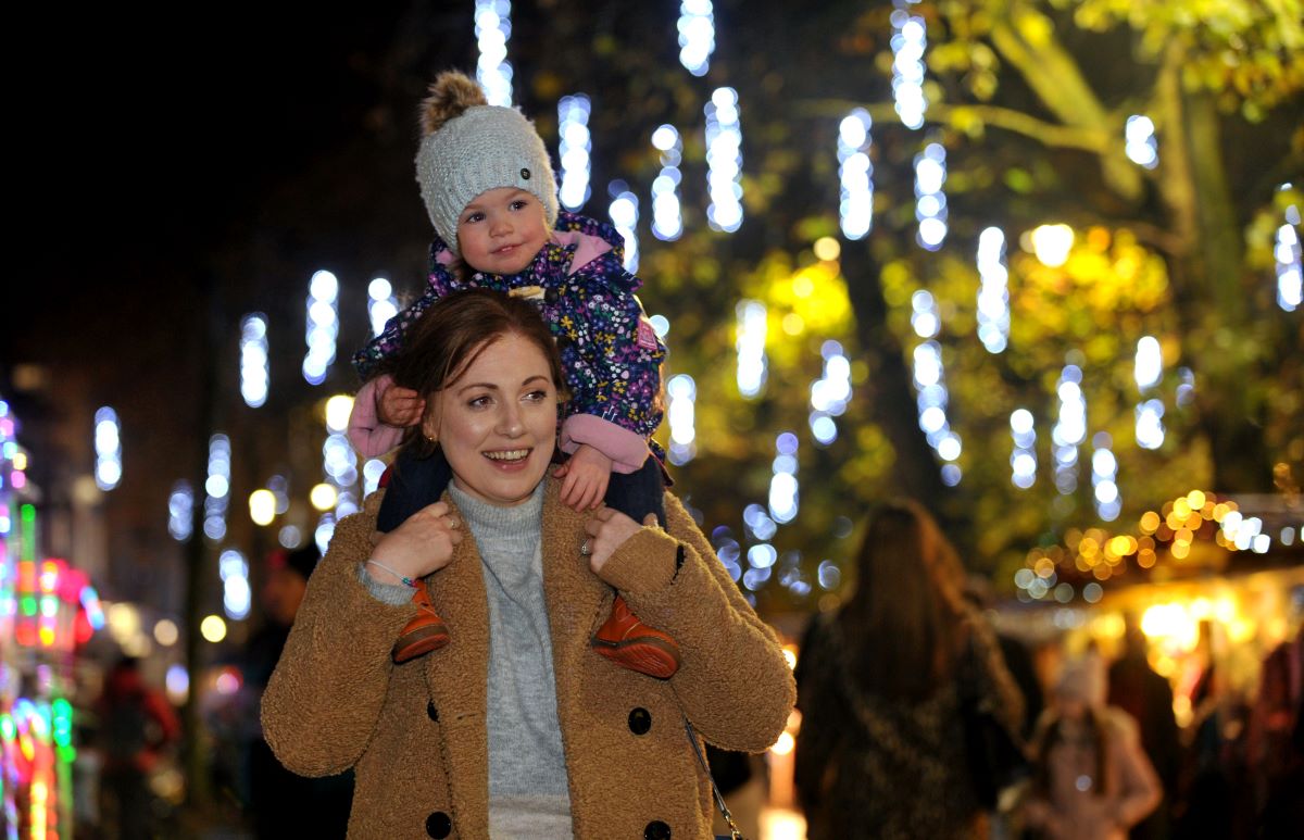 Child on mother's shoulder enjoying Christmas lights